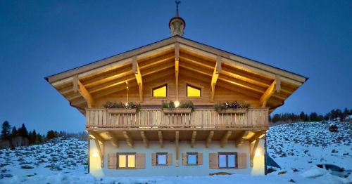 A two-story European-style Airbnb set in the hillside near Vail, Colorado, featuring a wooden deck and a vaulted roof, surrounded by a snowy landscape.