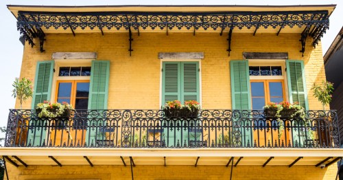 exterior of yellow row home with green shutters in the french quarter of New Orleans