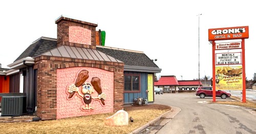 The tall roadside sign and brick exterior of Gronk's Grill and Bar stand under a cloudy sky in Superior, WI.