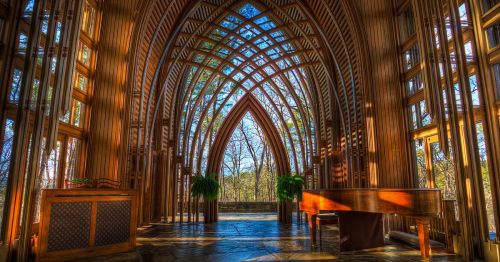 Inside the Mildred B Cooper Memorial Chapel in Arkansas, featuring exposed metal and wooden beams, with glass windows and pew benches.