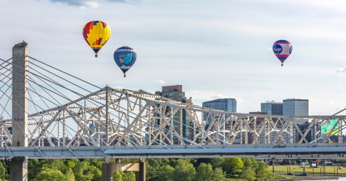 Bridge in Louisville, Kentucky, with three hot air balloons floating over the skyscrapers