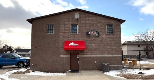 A red awning marks the rear brick exterior entrance to J&A Tap in North Liberty, IA.