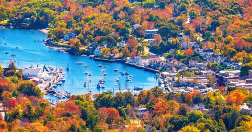 A calm cove curves into a small town surrounded by a forest awash in brilliant fall colors.
