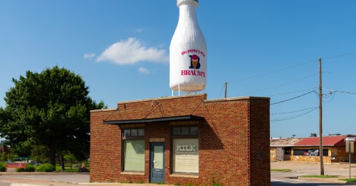 exterior of the milk bottle grocery, a skinny brick building with a large milk bottle on the roof in okc