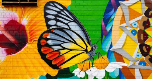 A colorful mural in MD, featuring a butterfly with orange and black wings, surrounded by bright florals and patterns.