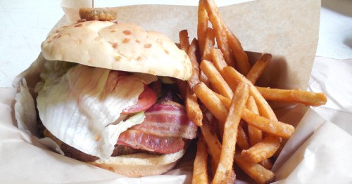 a burger toped with lettuce, tomato, and bacon and a side of fries at rattlesnake saloon in alabama