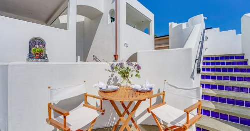 Private outdoor patio with small dining area and whitewashed stairs in a San Diego Airbnb, styled to capture the iconic architecture of Santorini.