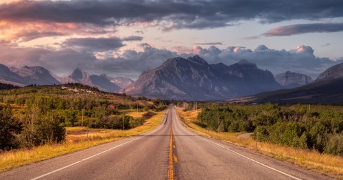 A scenic highway leading towards dramatic mountains and underrated travel destinations.