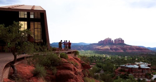 Tourists standing at the entrance of Chapel of the Holy Cross, overlooking the red rock landscape in Sedona, AZ.
