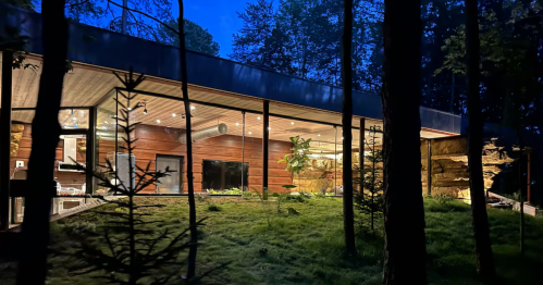 A night shot captures the illuminated stone interior visible through the modern glass façade of this South Bloomingville, Ohio Airbnb, offering a unique stay comparable to the caves of Cappadocia, Turkey.