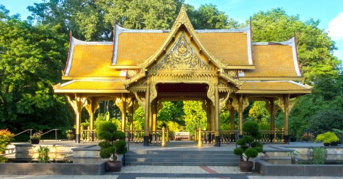 The ornate gold roof of the Thai Pavilion shines among lush green trees at Olbrich Botanical Gardens in Wisconsin.