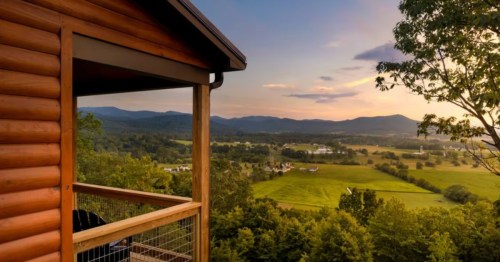 A mountainside cabin in Virginia with a view of the countryside and nearby mountains.