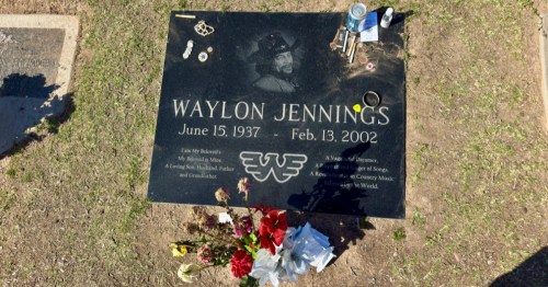 view of the black stone grave marker for waylon jennings with flowers and other trinkets left by fans