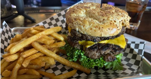 Massive burger with melted cheese and fries for the Whiskey Dicks Wichita eating challenge.