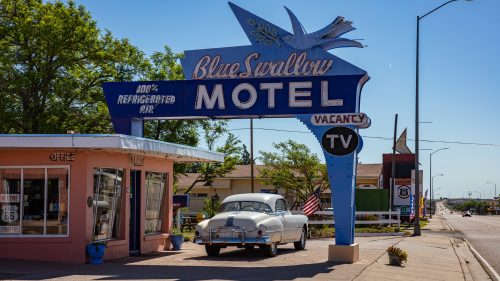 otel Blue Swallow next to mother road, route 66, a sunny day. An antique car is parked at the entrance.