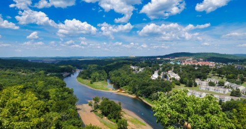 An aerial view of Brandon, with forests, a river, and the city in the background.