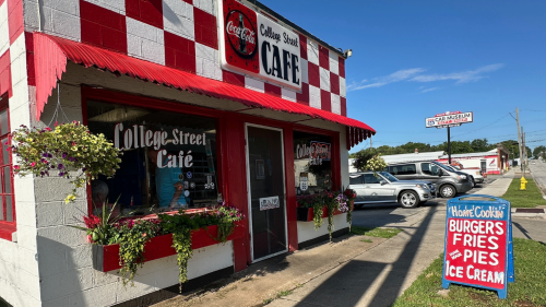 A shoebox-size restaurant is decorated with a cherry red checkerboard and colorful flower planters.
