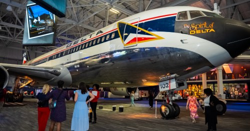 Visitors at the Delta Flight Museum stand beneath a large aircraft