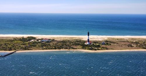 A picturesque view of the Fire Island National Seashore in Suffolk County, NY, and the Fire Island Lighthouse stands tall.