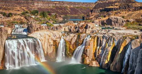A rainbow is visible in front of Shoshone Falls, a large waterfall in Twin Falls, Idaho.