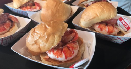 An assortment of lobster rolls, served in paper serving trays.
