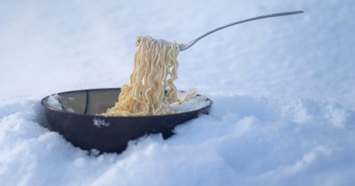 Ramen noodles frozen on a fork and surrounded by snow.