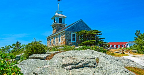 An old-fashioned brick church atop a rocky hill on an island.