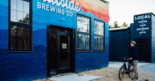 A cyclist stands in front of Trailside Brewing on the side of the Ecusta Trail