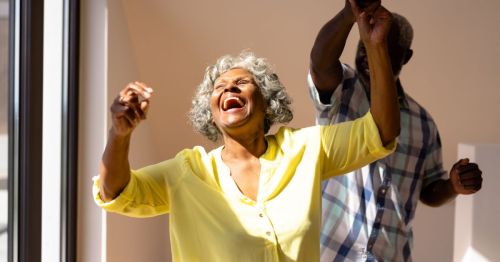 A retired couple in Mississippi joyfully dancing and expressing happiness and enjoyment indoors.