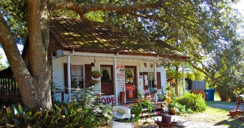 A charming bed and breakfast in Breaux Bridge, LA, surrounded by greenery and trees, rustic trinkets, and potted plants.