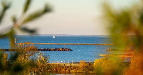 The Ashland Breakwater Lighthouse sits on a long stone pier surrounded by the blue waters of Chequamegon Bay, WI.