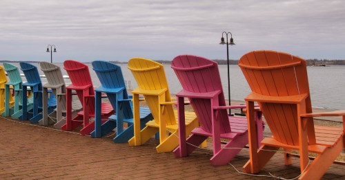 Colorful chairs in front of a lake under a grey sky