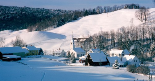A small town with red and white buildings is blanketed by what looks like undisturbed snow.