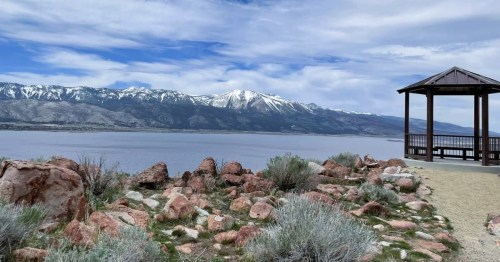 Scenic view of Washoe Lake in NV, with a rocky shoreline and snow-capped mountains in the background.