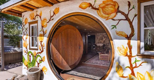 Close-up of a Hobbit-style Airbnb in Arizona with large circular door framed by painted magnolia branches.