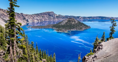 Secluded island in Oregon with clear turquoise waters surrounded by cliffs and evergreen trees.