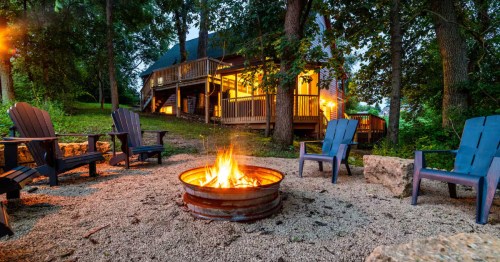 Four lawn chairs surround a fire pit outside an Airbnb lodge