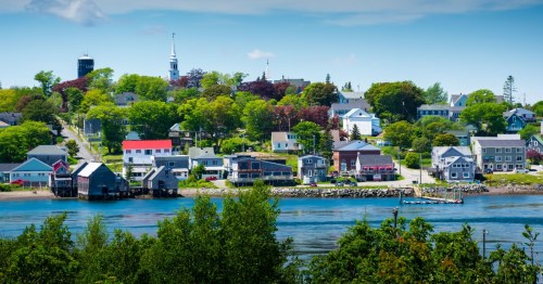 A waterfront town with small, quaint houses sit under a clear sky.