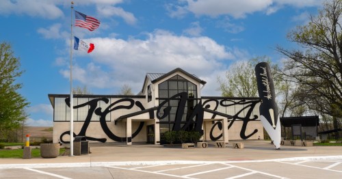 Modern Tiffin, Iowa rest area building featuring giant "IOWA" script art and a large quill pen sculpture out front.