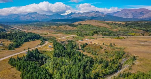 Aerial view of rolling hills, forests, and mountains surrounding a secluded Montana countryside Airbnb.