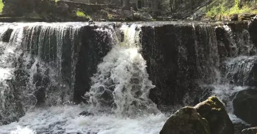 A waterfall flows over a small dam.