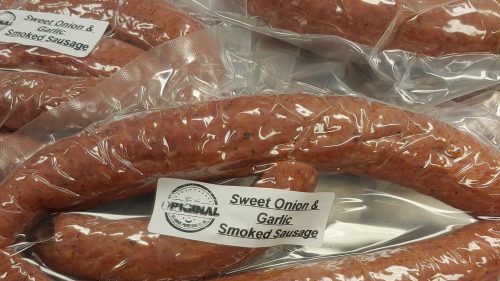 Several packages of sweet onion and garlic smoked sausage, labeled and arranged on a surface.