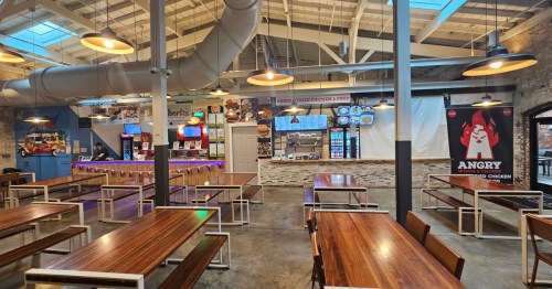 An interior shot of a food hall with tables and various restaurants.