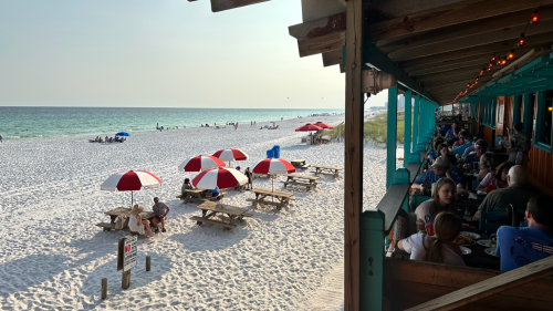 Row of tables overlooking a white, sandy beach and ocean