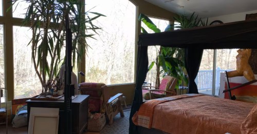 An old-fashioned canopy bed in Scituate, Rhode Island, surrounded by art sculptures.