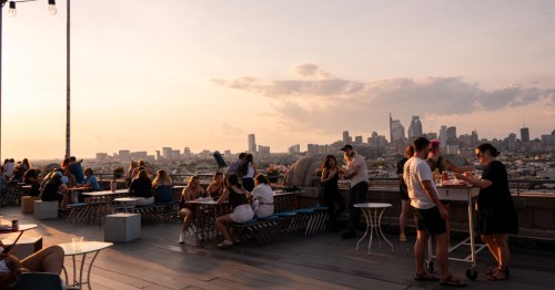 Patrons enjoy the sunset and skyline views from the communal seating at Bok Bar in Philadelphia, Pennsylvania.