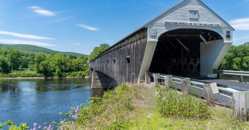 A lengthy covered bridge spanning a river in Windsor, Vermont.
