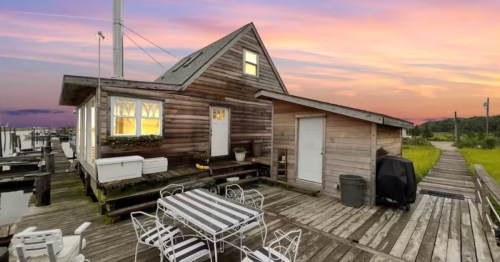 A wood-paneled cabin only feet away from the water, located on a dock at sunset