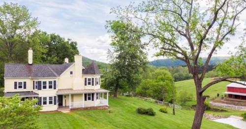 A large, historic white farmhouse to the left of an expanse of sprawling farmland in Knoxville, Maryland