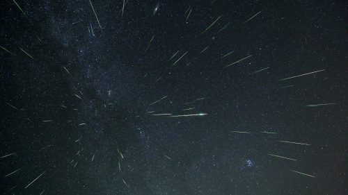 A starry night sky filled with streaks of light from meteors, creating a dynamic and vibrant celestial scene.